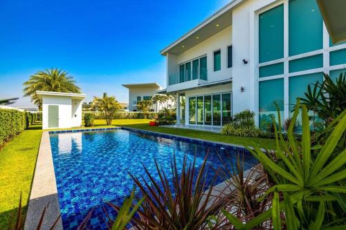 a house with a swimming pool in front of a house at Modern 3 bedroom Pool Villa PG19 in Cha Am