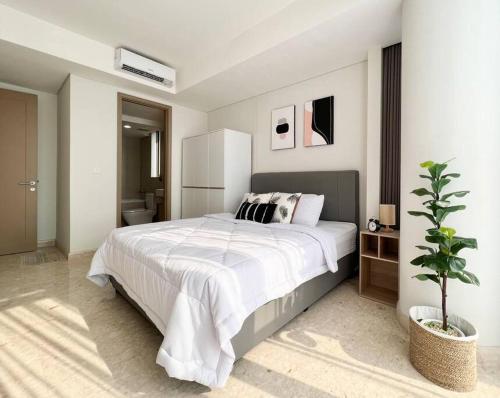 een witte slaapkamer met een groot bed en een plant bij Stylish Seaview 3 BR Condo at PIK in Jakarta