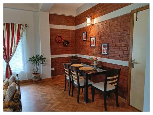 a dining room with a brick wall and a table and chairs at Sha Ri Loum Homestay in Shillong