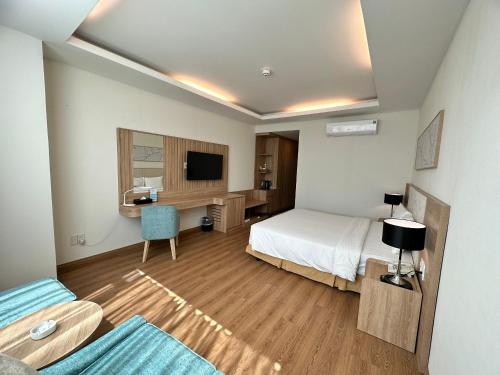 a bedroom with a bed and a desk with a television at Muong Thanh Holiday Vung Tau Hotel in Vung Tau