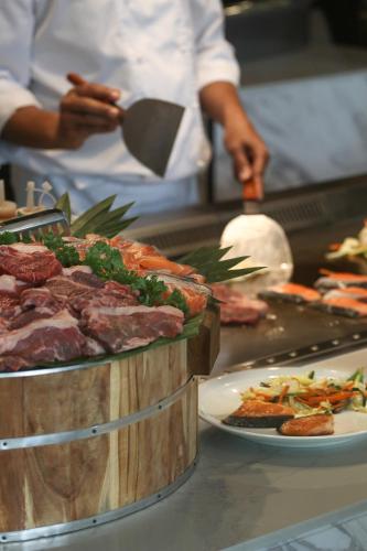 a chef preparing food in a kitchen with a plate of meat at Chatrium Grand Bangkok in Bangkok