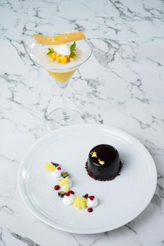 a white plate with a dessert and a wine glass at Chatrium Grand Bangkok in Bangkok