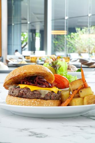 a plate with a hamburger and french fries and a salad at Chatrium Grand Bangkok in Bangkok
