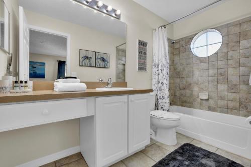 a bathroom with a sink and a toilet and a bath tub at Large 6BR Themed Family Villa Near Disney world in Kissimmee