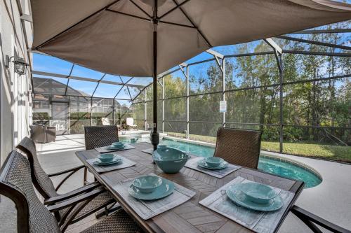 a dining table with an umbrella next to a pool at Large 6BR Themed Family Villa Near Disney world in Kissimmee