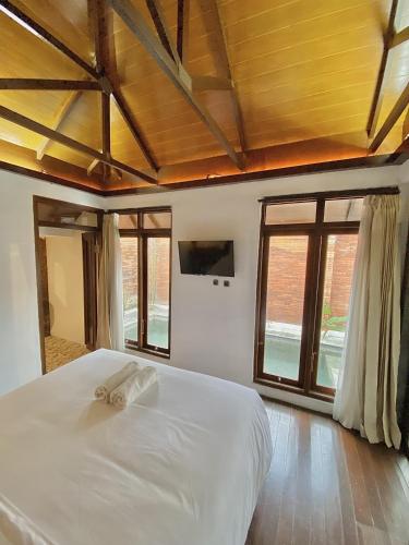 a bedroom with a large white bed with windows at chrome hotel & resort solo in Tjolomadu