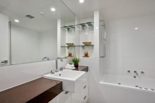 a white bathroom with a sink and a tub at Elevation 2 bedroom with guest room gas fire and mountain views in Thredbo