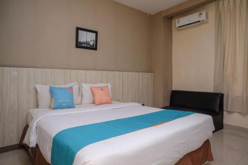 a bedroom with a large bed and a chair at Sans Hotel Lynt Makassar in Makassar