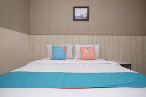 a bed with three pillows on top of it at Sans Hotel Lynt Makassar in Makassar