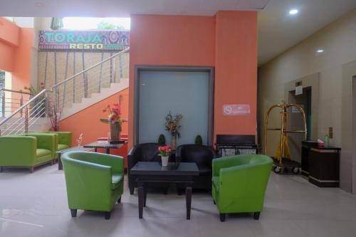 a waiting room with green chairs and a table at Sans Hotel Lynt Makassar in Makassar