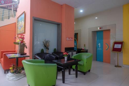 a waiting room with green chairs and a table and a lobby at Sans Hotel Lynt Makassar in Makassar