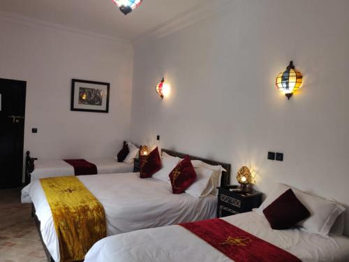 Habitación de hotel con 3 camas y luces en la pared en Riad Dar Foundouk and Spa, en Marrakech