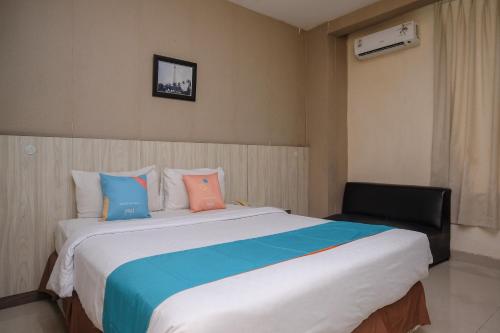 a bedroom with a large bed and a chair at Sans Hotel Lynt Makassar in Makassar