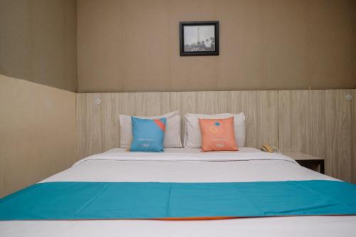 a bed with four pillows on top of it at Sans Hotel Lynt Makassar in Makassar