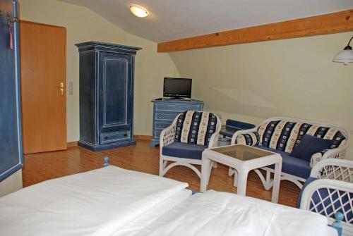 a bedroom with a bed and two chairs and a tv at DEB 021 Hotel in Juliusruh auf Rue in Juliusruh