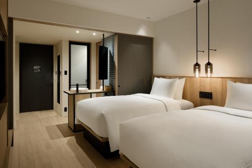 2 Betten in einem Hotelzimmer mit weißer Bettwäsche in der Unterkunft Fairfield by Marriott Okayama Tsuyama in Tuyama