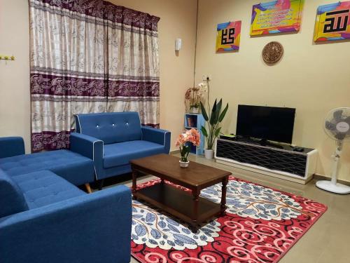 sala de estar con sofás azules y TV en MUAZDIANA HOMESTAY di KUALA NERUS, GONG BADAK, en Kampong Tanjong Gelam