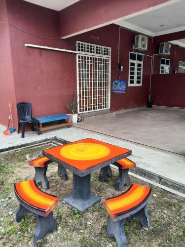 a picnic table and two chairs in front of a building at MUAZDIANA HOMESTAY di KUALA NERUS, GONG BADAK in Kampong Tanjong Gelam