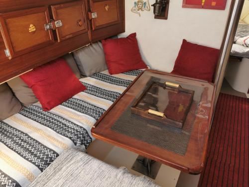 a small bed with a table and red pillows at stlocavoile 2, Seuls à bord d un voilier in Porto-Vecchio