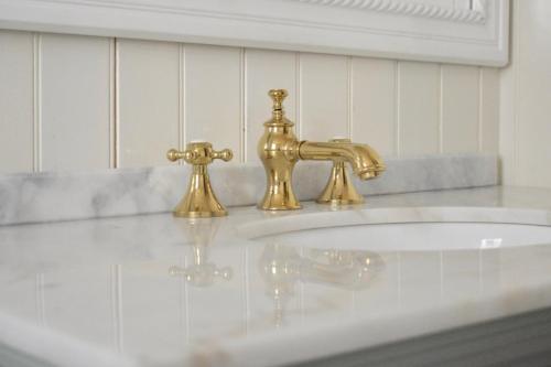 un lavandino in bagno con due rubinetti d'oro di Family Friendly Montclair Hideaway a Montclair