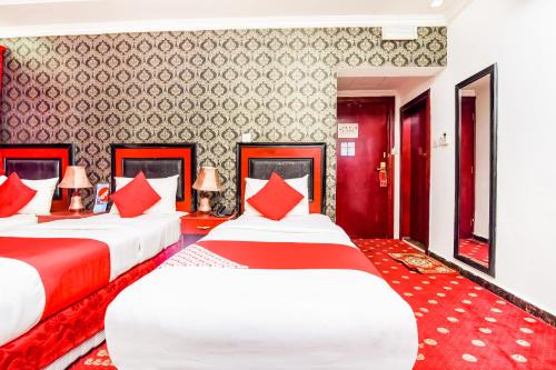 dwa łóżka w pokoju z czerwonym i białym w obiekcie OYO 492 Gulf Star w Dubaju