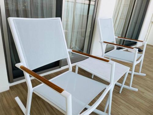 duas cadeiras brancas sentadas uma ao lado da outra num quarto em 1204 ブランシエラ那覇曙プレミスト em Nakanishi