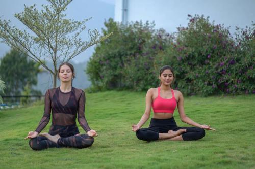 two women sitting in the grass doing yoga at Sprise Munnar Resort and Spa in Munnar