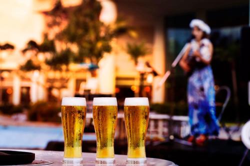 three glasses of beer sitting on a table at Laguna Garden Hotel in Ginowan
