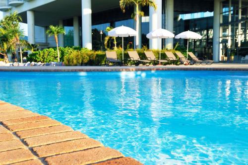 a swimming pool with chairs and umbrellas in a building at Laguna Garden Hotel in Ginowan