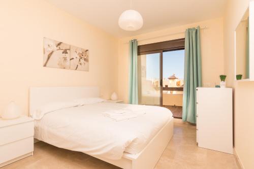 een witte slaapkamer met een bed en een raam bij 2114-Apt with nice terrace with pool view in Manilva