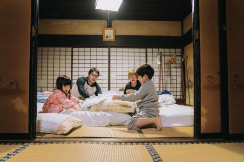 eine Gruppe von Personen, die in einem Zimmer auf Betten sitzen in der Unterkunft Stay and Discover Nishinoya in Senboku