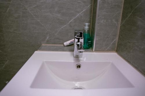 a white sink in a bathroom with a green bottle at Rostron House in Manchester
