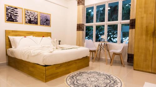 een slaapkamer met een bed en een tafel en stoelen bij Palm Rest Maldives in Magoodhoo