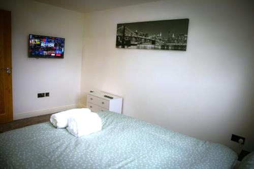 a bedroom with a bed and a tv on the wall at Rostron House in Manchester