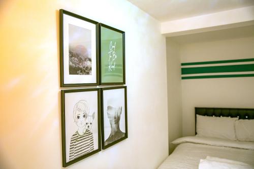 four framed pictures on a wall above a bed at Rostron House in Manchester