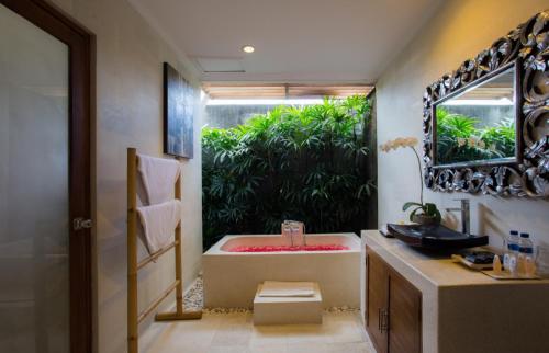 ein Badezimmer mit Badewanne, Waschbecken und Spiegel in der Unterkunft Sandi Agung Villa in Seminyak