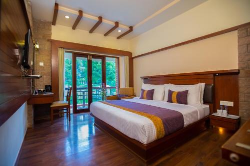 a bedroom with a large bed and a balcony at Hotel Kodai International in Kodaikānāl