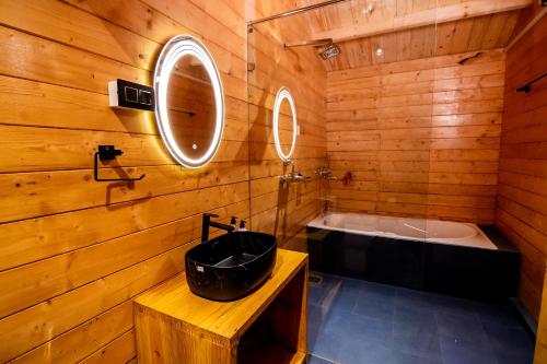 a wooden bathroom with a tub and a sink at Tranquill Riverside Luxury Cottages With Bathtub, Candolim in Candolim