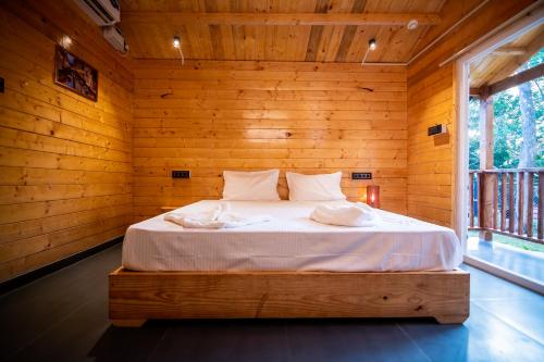 a bedroom with a bed in a wooden wall at Tranquill Riverside Luxury Cottages With Bathtub, Candolim in Candolim