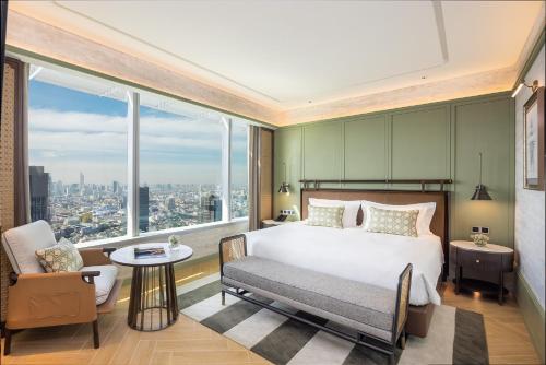 a bedroom with a bed and a chair and a large window at Eastin Grand Hotel Phayathai in Bangkok
