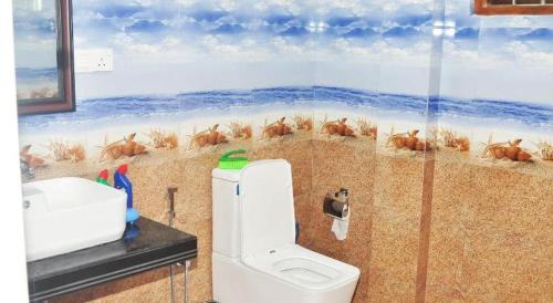 a bathroom with a toilet and a painting of a beach at Gold sand Resort in Bentota