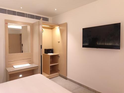 ヴィシャカパトナムにあるSignature Hotelsのベッドルーム1室(ベッド1台、壁掛けテレビ付)