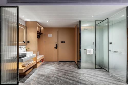 uma casa de banho com uma cabina de duche em vidro e um lavatório. em Jinshi Hotel em Guangzhou