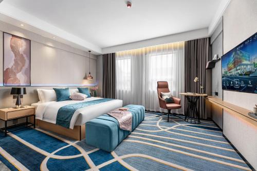 um quarto de hotel com uma cama e uma cadeira em Jinshi Hotel em Guangzhou