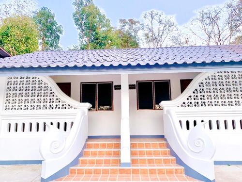 a white house with a blue roof and stairs at Doithinnan Resort in Nan