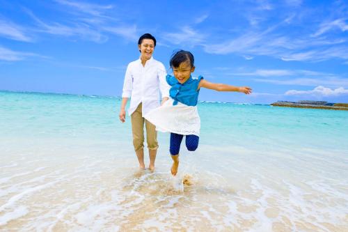 a man and a child playing in the water on the beach at Laguna Garden Hotel in Ginowan