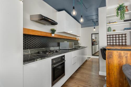 una cucina con armadietti bianchi e piano cottura di Buitenhof 301 a Città del Capo