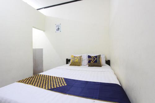 a white room with a bed with blue and yellow pillows at OYO 92231 Penginapan Tanjung Alang Syariah in Makassar