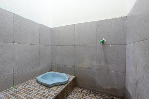 La salle de bains est pourvue de toilettes bleues sur un mur carrelé. dans l'établissement OYO 92231 Penginapan Tanjung Alang Syariah, à Makassar