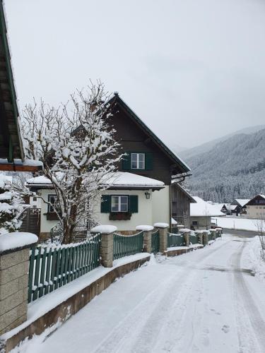 a snow covered street in front of a house at Ferienhaus Waldglück in Gosau